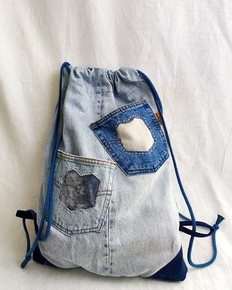 Luna-Jeans-b Un bolso de mezclilla con cordón y bolsillos.