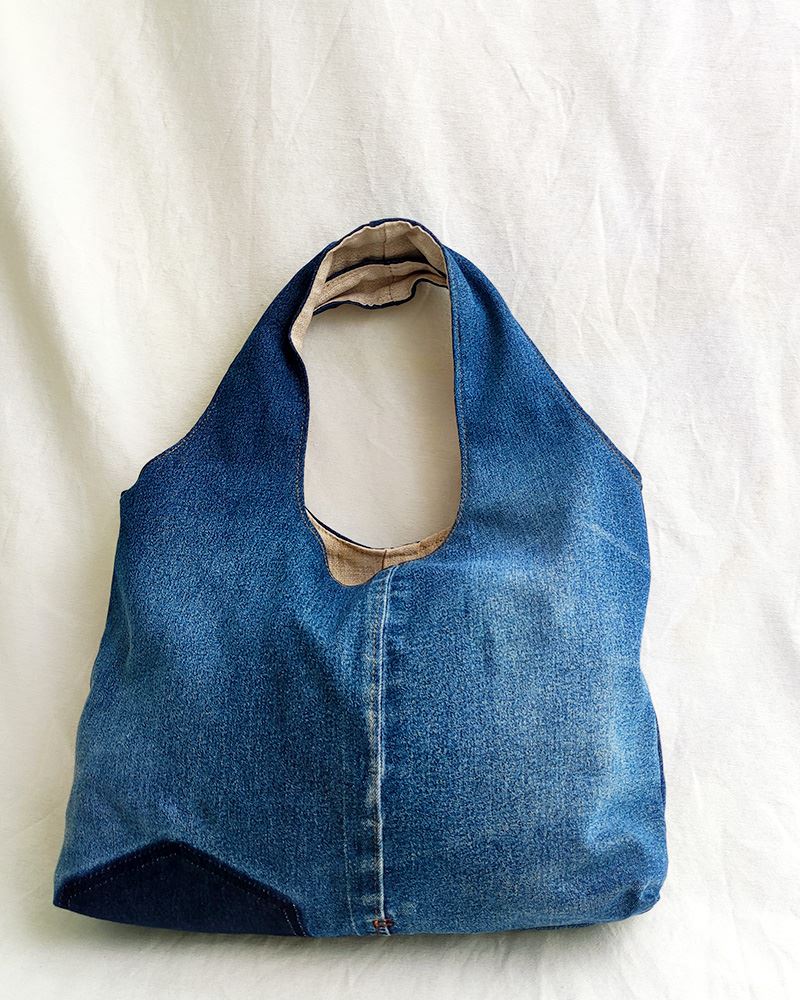 Sol-Jeans-b Una bolsa de mezclilla azul sobre una superficie blanca.
